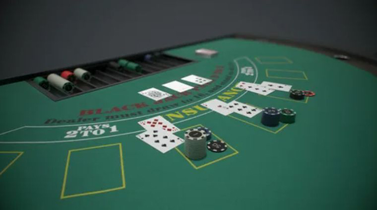Stół do blackjacka z zaznaczonymi polami do obstawiania, żetonami i kartami gracza oraz krupiera